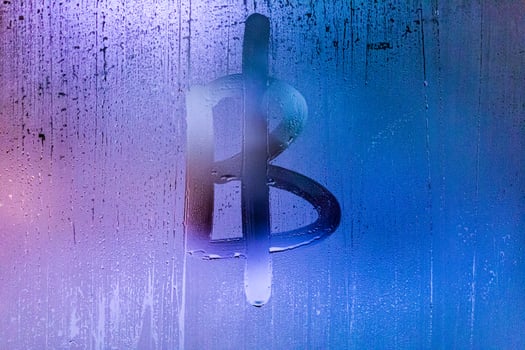bitcoin symbol - handwritten on wet glass of night window photo