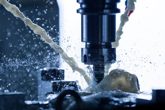 a process of vertical cnc steel milling with external water coolant streams, splashes and a lot of metal chips, high contrast, shallow depth of field. photo