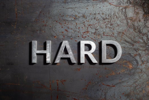 the word hard laid with silver metal letters on rusted burnt iron flat surface background photo