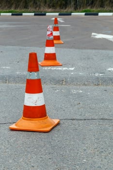 orange traffic cones on dry gray asphalt road surface - close-up with selective focus photo