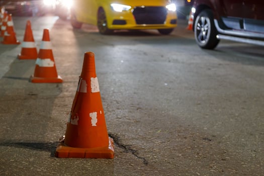 orange traffic cones row on night city asphalt - close-up with selective focus photo