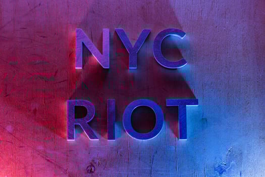 The words NYC riot laid with metal letters on flat plywood surface under red and blue police lights. Concept. photo
