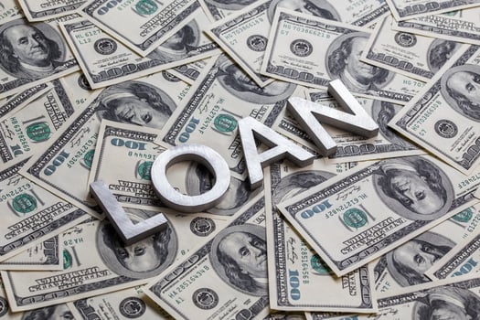 The word LOAN laid with aluminium letters on the US dollar banknotes background - with selective focus photo