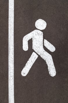 White walking person street sign on grey city asphalt road with vertical stripe photo