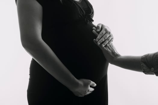 Young adult pregnant woman in white clothes touching big naked belly with hands. Showing shape. Pregnancy concept. Expectation time. Closeup. Isolated on light gray wall background. photo