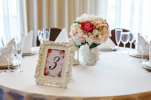 Fancy table set for dinner with flower composition in restaurant, luxury interior background. Wedding elegant banquet decoration and items for food arranged by catering service on white table. photo