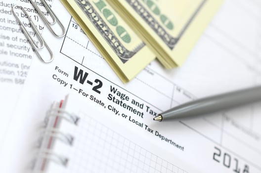 The pen, notebook and dollar bills is lies on the tax form W-2 Wage and Tax Statement. The time to pay taxes photo