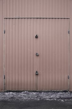 Texture of a metal brown wall with a gate closed for three locks photo