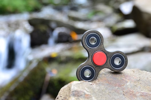 The wooden spinner lies on the rocks against the background of a small waterfall and a river photo
