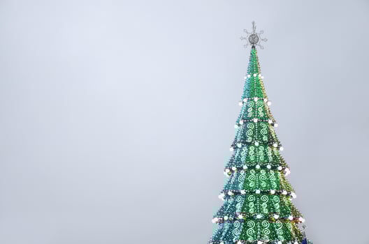 A fragment of a huge Christmas tree with many ornaments, gift boxes and luminous lamps. Photo of a decorated Christmas tree close-up with copy space