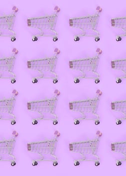 Shopping addiction, shopping lover or shopaholic concept. Many small empty shopping carts perform a pattern on a pastel colored paper background. Flat lay composition, top view photo