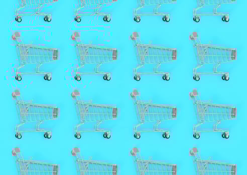 Shopping addiction, shopping lover or shopaholic concept. Many small empty shopping carts perform a pattern on a pastel colored paper background. Flat lay composition, top view photo