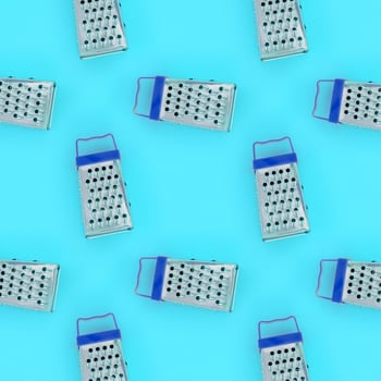 Small stainless steel graters lies on a pastel colored paper. Kitchen accessories. Tools for cooking. Flat lay top view photo
