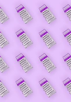 Small stainless steel graters lies on a pastel colored paper. Kitchen accessories. Tools for cooking. Flat lay top view photo