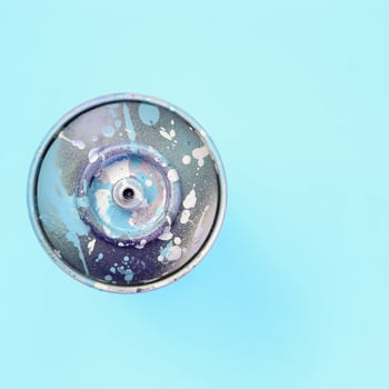 Used spray can with blue paint drips lie on texture background of fashion pastel blue color paper photo