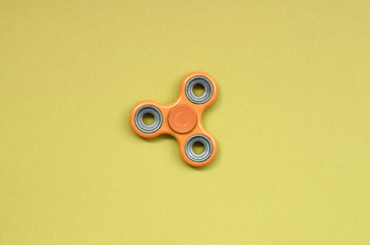 orange fidget spinner lies on texture background of fashion pastel orange color paper photo