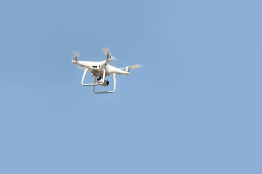 Big white drone hovering in a bright cloudless blue sky photo