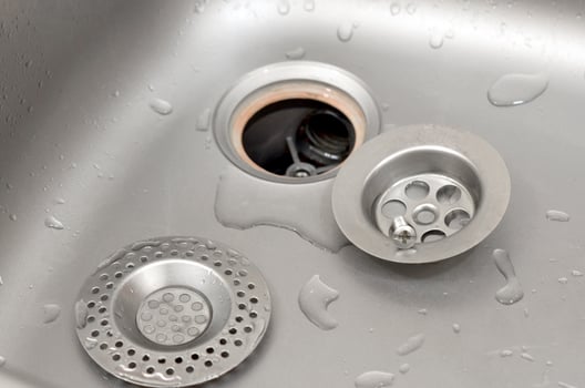 Silvery kitchen sink with a disassembled protective filter during the repair process photo
