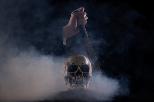 Halloween human skull on an old wooden table over black background. Shape of skull bone for Death head on halloween festival which show murderer knife kill dead sentence, copy space photo