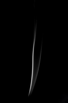 A single white smoke burn from incense, shot in studio with dark black background, for design and religion concept photo