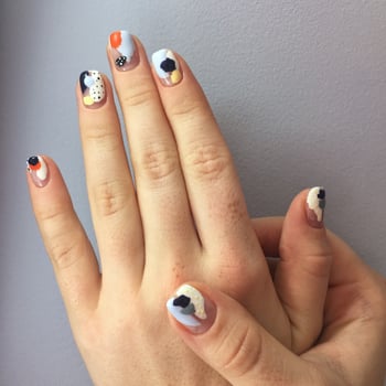 Manicure of different colors on nails. Female manicure on the hand on blue background photo