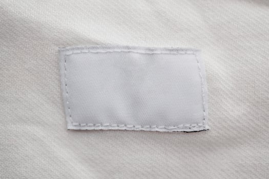 White blank clothing label on cotton shirt background photo