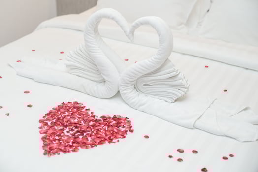 Swan towel on bed and rose petals in  heart shape for honeymoon or wedding anniversary, romantic feeling. photo
