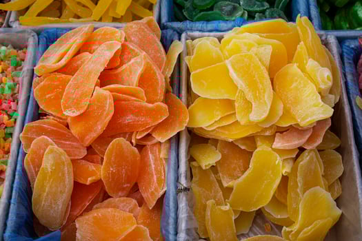 Candied fruits, mango pieces in yellow and orange colors. A pile of candied slices in boxes at the market. photo