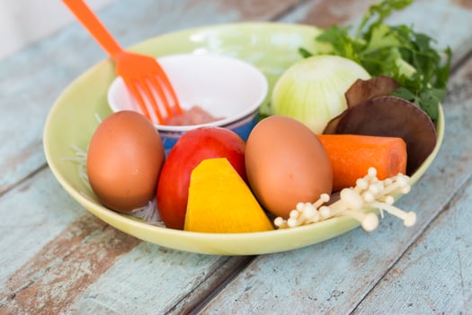 Fresh vegetables, eggs and pork chops. On blue wooden photo