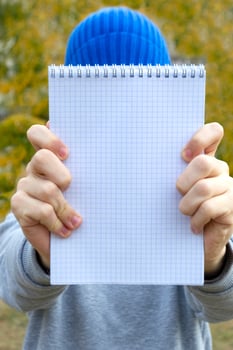 Teenager boy holding a notebook in his hands outdoor. Selective focus photo