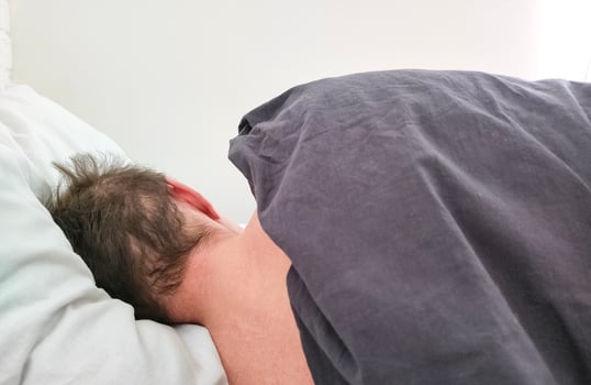 Man sleeping in bed under blanket in the morning. photo