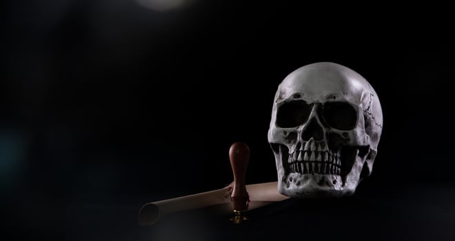 Halloween human skull on an old wooden table over black background. Shape of skull bone for Death head on halloween festival which show lastwill letter stamp interitance ghost spirit, copy space photo