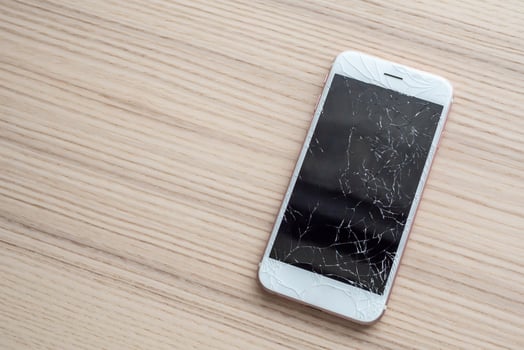 broken glass of mobile phone screen on wooden background photo