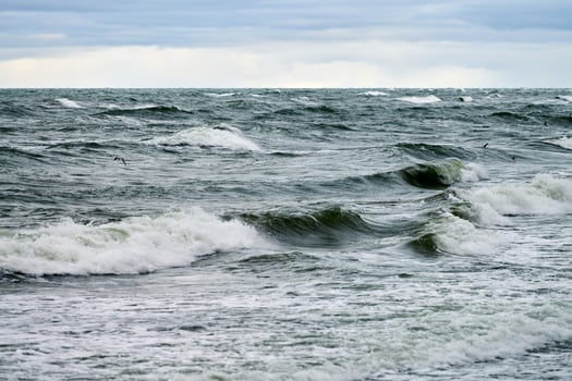 Blue sea with foaming waves and cloudy sky, seascape photo