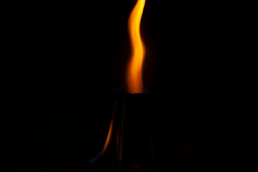 Flames in dark. One flame on black background. Ignition details. Fire burns yellow. photo