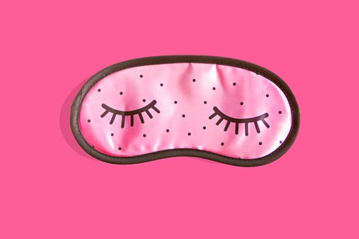 Pink sleep mask accessories for girls and young women with closed eyes on pink background. Top view, flat lay. Concept of eye protection for good dreams and sleep. photo