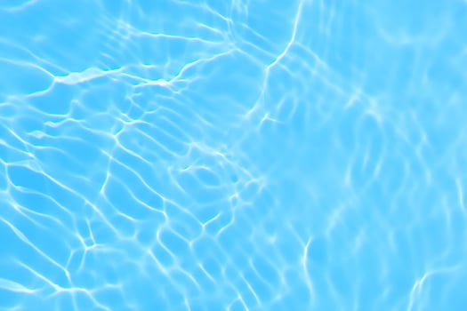 Defocus blurred transparent blue colored clear calm water surface texture with splash, bubble. Shining blue water ripple background. Surface of water in swimming pool. Blue bubble water shining. photo