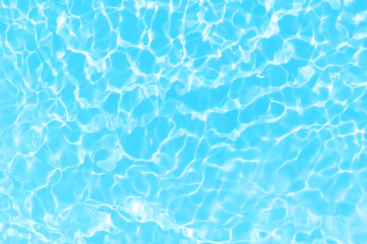 Defocus blurred transparent blue colored clear calm water surface texture with splash, bubble. Shining blue water ripple background. Surface of water in swimming pool. Blue bubble water shining. photo