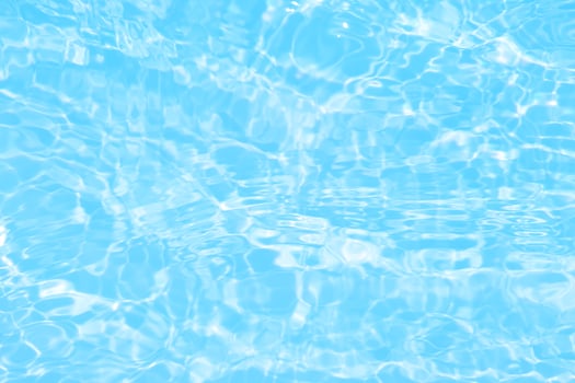 Defocus blurred transparent blue colored clear calm water surface texture with splash, bubble. Shining blue water ripple background. Surface of water in swimming pool. Blue bubble water shining. photo