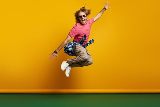 Stylish young man looking excited while jumping against yellow background photo