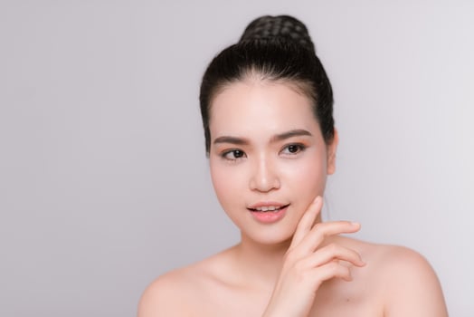 Happy young woman face with clear skin on gray background, closeup portrait photo