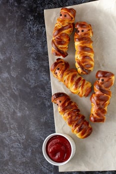 Scary sausage mummies in dough for kids party. Funny crazy Halloween food for children. photo