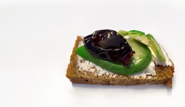 Healthy food, cereal bread toast with avocado, cream cheese and sun-dried plums on white background, for breakfast or keto diet, copy space photo