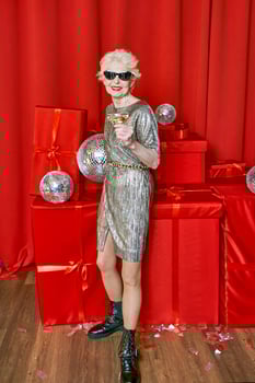 Senior stylish elegant woman with glass of sparkling wine on red background. Party, fashion, celebration, anti age concept photo