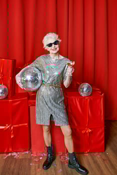 Senior stylish elegant woman with glass of sparkling wine on red background. Party, fashion, celebration, anti age concept photo