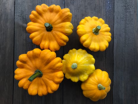 Five orange patissons on a wooden background. Autumn harvest of orange squash. Healthy food concept. View from above. Flat lay. photo
