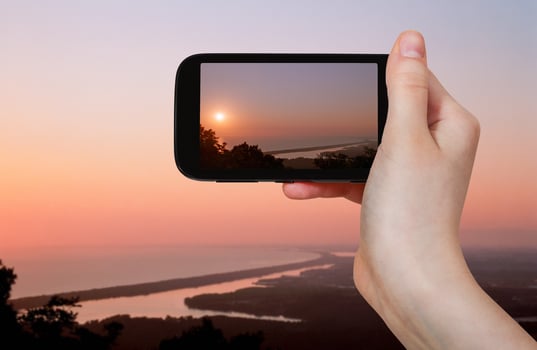 tourist taking photo of salt lake at pink sunset