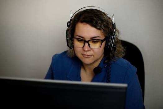 A serious call center operator is talking to a client while looking at a computer screen in close-up. photo