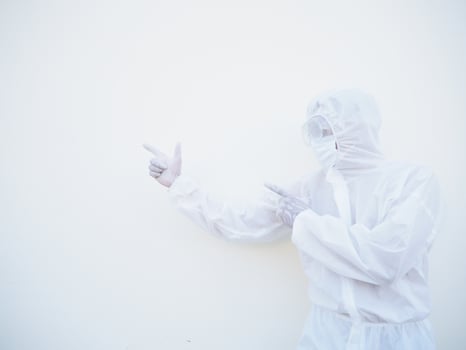 Asian male doctor or scientist in PPE suite uniform showing pointing two fingers away at copy space while standing and looking forward. coronavirus or COVID-19 concept isolated white background photo
