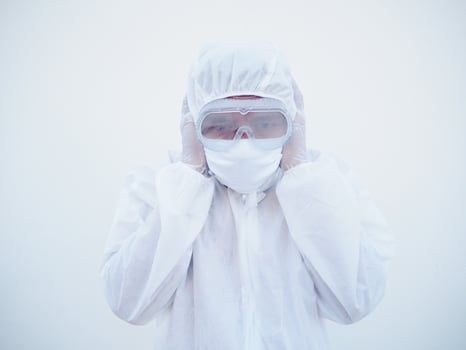 Asian doctor or scientist in PPE suite uniform covers ears with hands. Danger of coronavirus or COVID-19 concept isolated white background photo